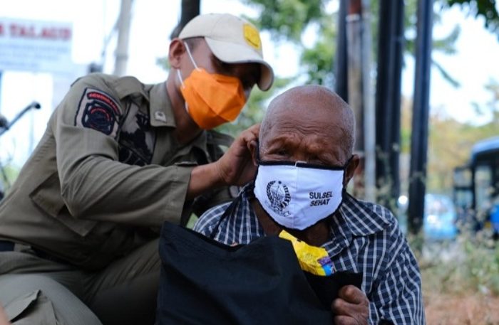 Saat petugas memakaikan masker untuk Warga di Makassar.